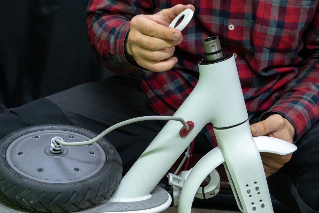 electric scooter repair workshop. the master holds in his hand the broken part of the scooter and motor wheel. replacing the tube and tires. modern environmentally friendly mode of transport.